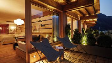 Ein modernes Interieur mit Holzbalken, einem großen Fenster und einer Sitzecke mit Tisch und Stühlen.