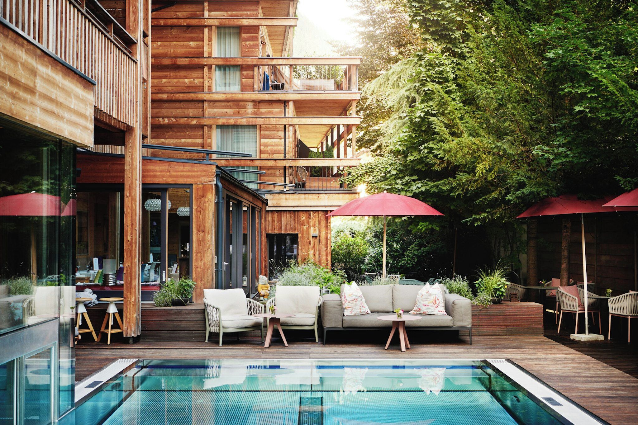 Ein Holzgebäude mit Pool, Sitzgelegenheiten im Freien und viel Grün.