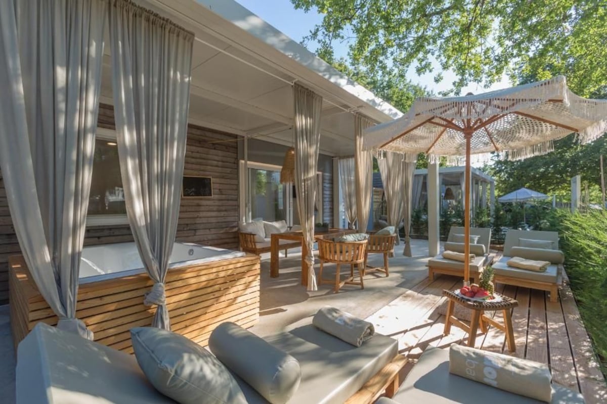 A sunlit outdoor seating area with wooden furniture, a covered table, and a decorative umbrella.