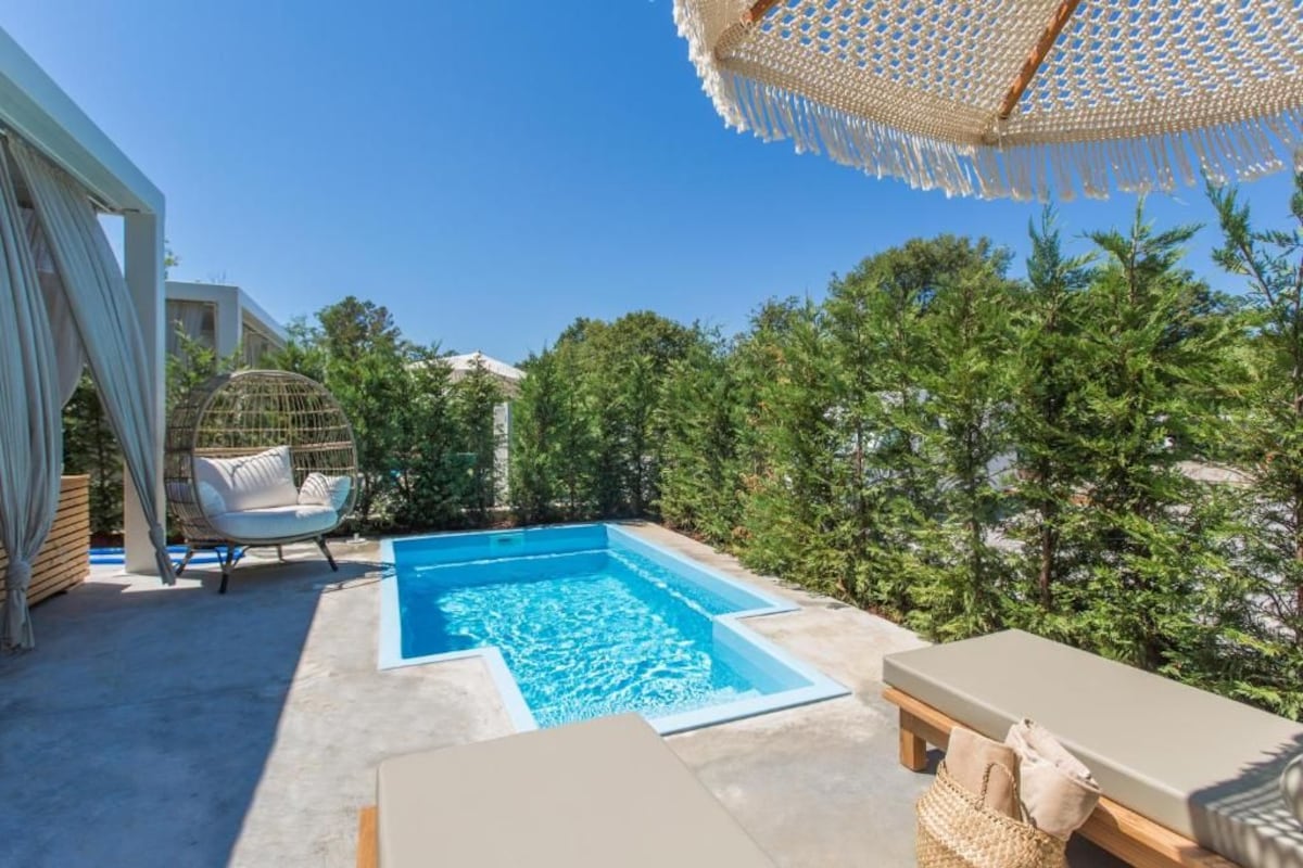 A swimming pool with lounge chairs and a pergola.