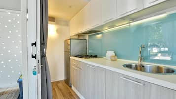 Une cuisine moderne dotée d’un évier en acier inoxydable, d’une cuisinière à gaz et de meubles de rangement en bois clair.