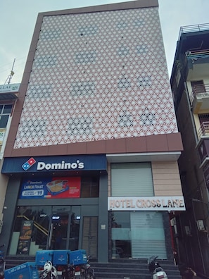 A building with a patterned facade, a Domino's Pizza outlet, and a sign for Hotel Cross Lane. - HOTEL CROSSLANE (KOTA)