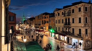 Una calle nocturna con edificios, tiendas y gente.