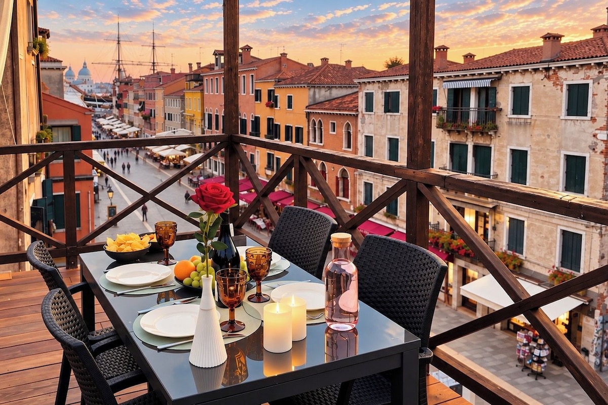 Un área de comedor al aire libre con una mesa dispuesta para dos, con vista a una calle con edificios históricos.
