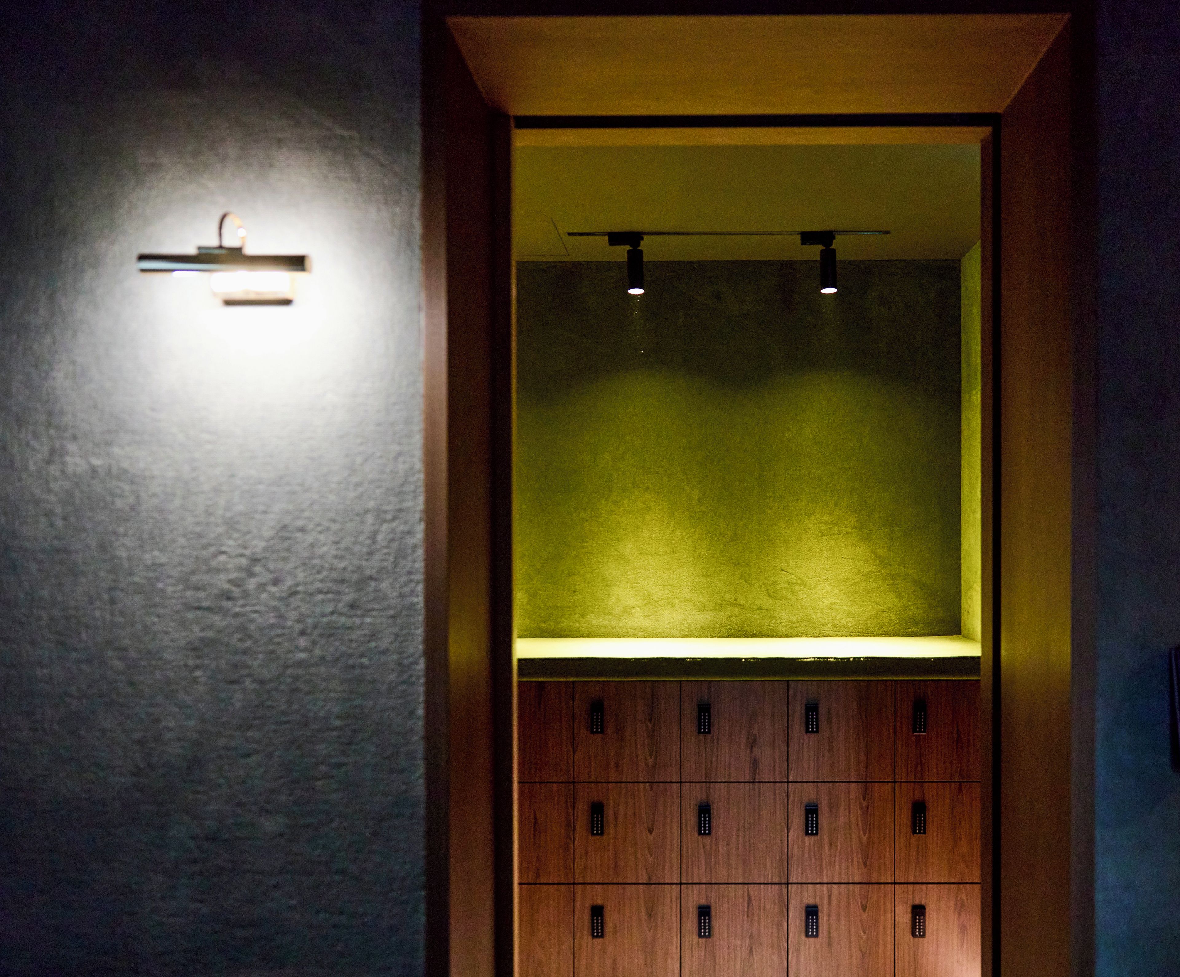 Una habitación con un armario de madera y una lámpara en la pared.