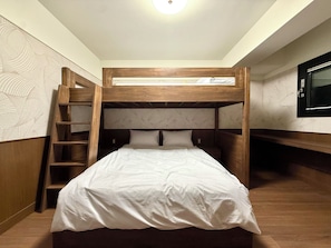 Una cama litera con escalera de madera, una cama baja debajo y un televisor en la pared.