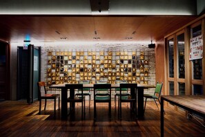 Quarto com piso de madeira, uma mesa com cadeiras e parede com vários retratos emoldurados.