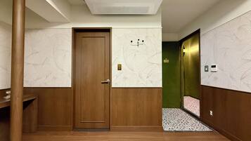 A hotel hallway with a wooden door, patterned wallpaper, and a tiled floor.