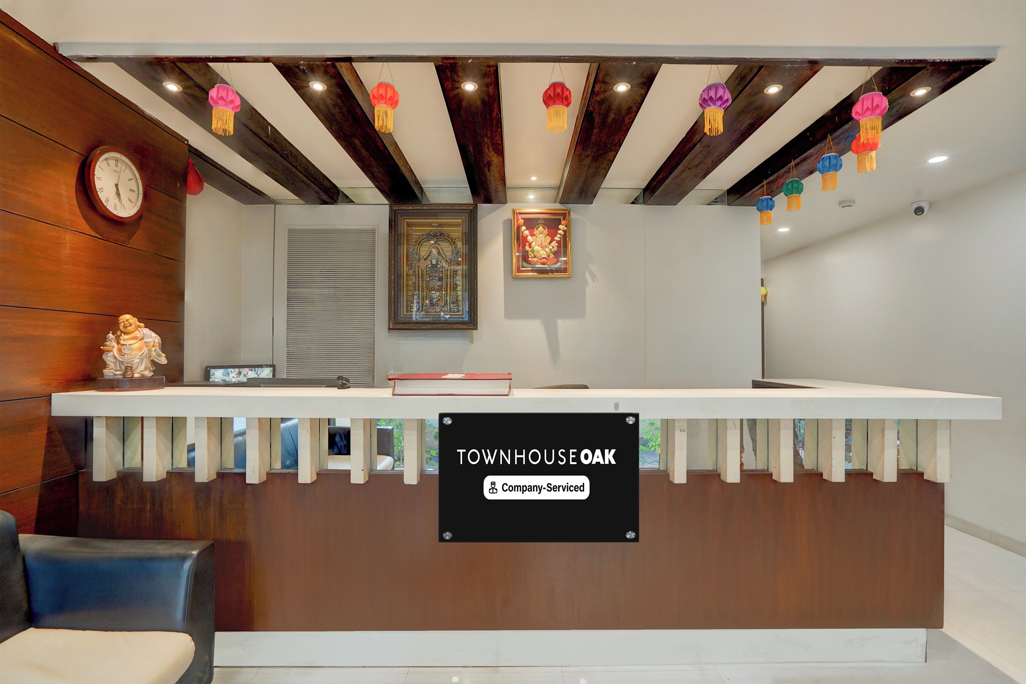 A reception desk with a sign indicating 'Company-Serviced' and a clock on the wall.