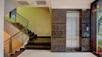 Ein modernes Interieur mit einer Treppe, einem Glastreppenaufzug und einer Wand mit Steinmuster.