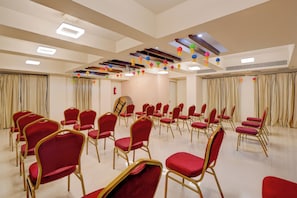 A conference room with rows of red chairs, a fire extinguisher, and ceiling lights. - Townhouse Oak Pune Railway Station (Pune)