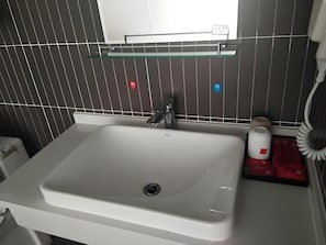 Casa de banho com lavatório branco, espelho e porta-toalhas.