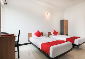 Une chambre d’hôtel avec deux lits, un bureau, une chaise et une armoire.