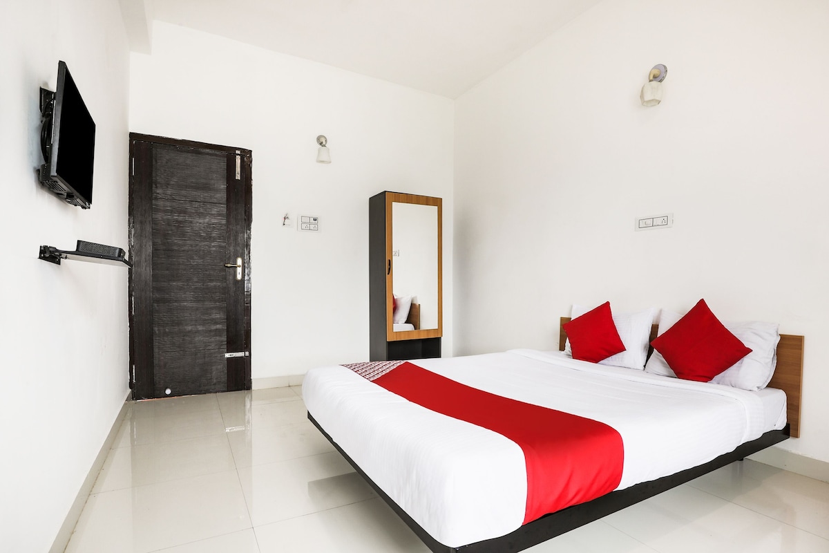 Une chambre d’hôtel avec un lit, un téléviseur fixé au mur, une porte et un miroir.