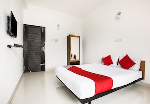 Une chambre d’hôtel avec un lit, un téléviseur fixé au mur, une porte et un miroir.