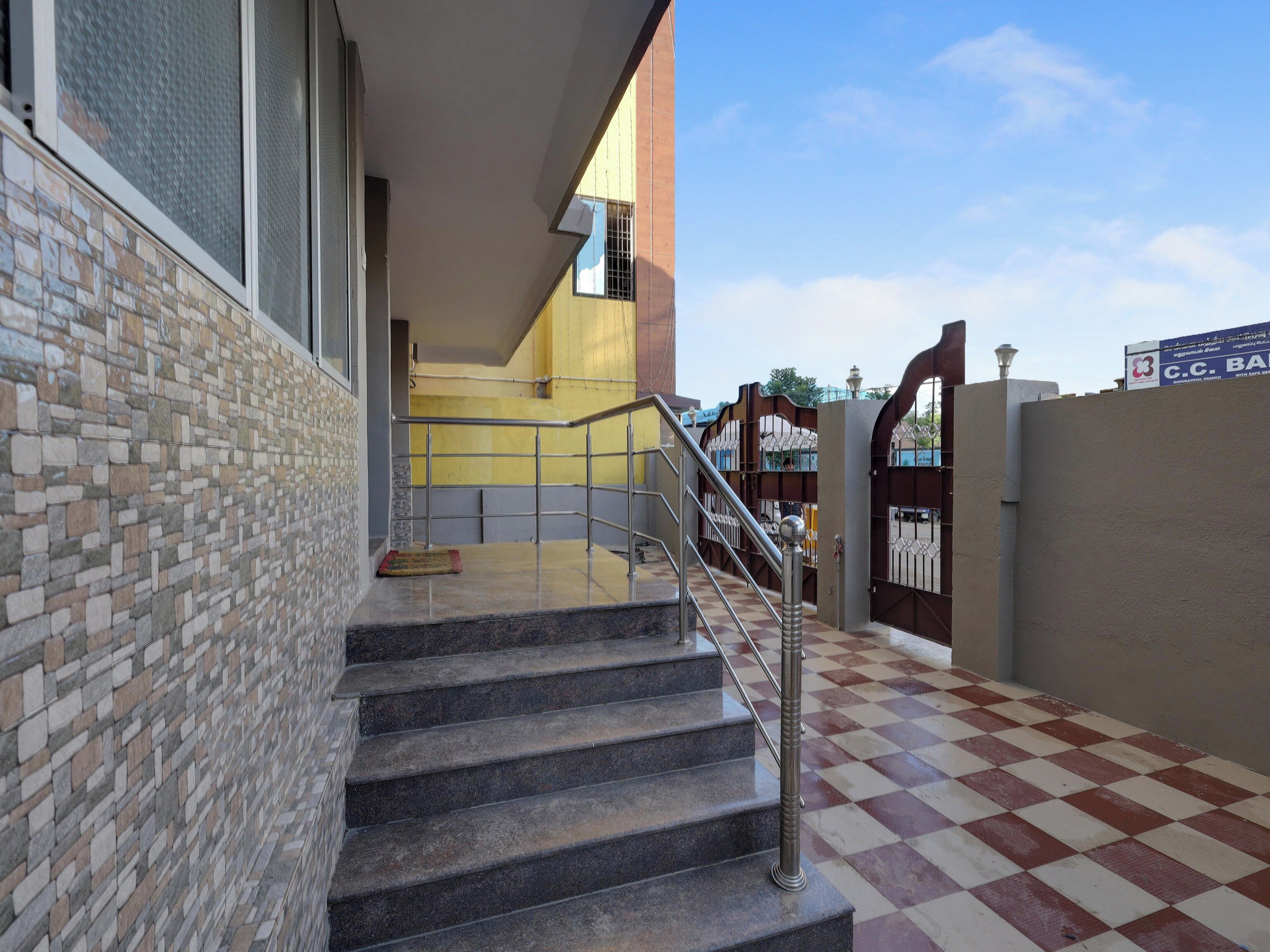 Una escalera con barandillas metálicas que conduce a un acceso con portón.