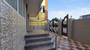 Una escalera con barandillas metálicas que conduce a un acceso con portón.