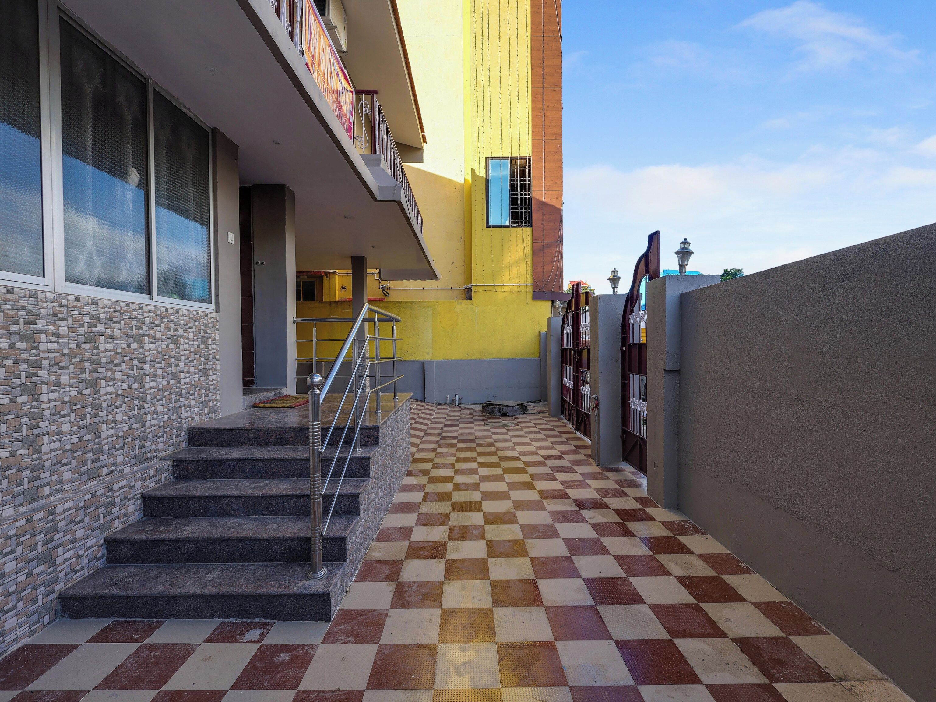 Entrada de hotel con piso de cuadros, una escalera y una pared amarilla.