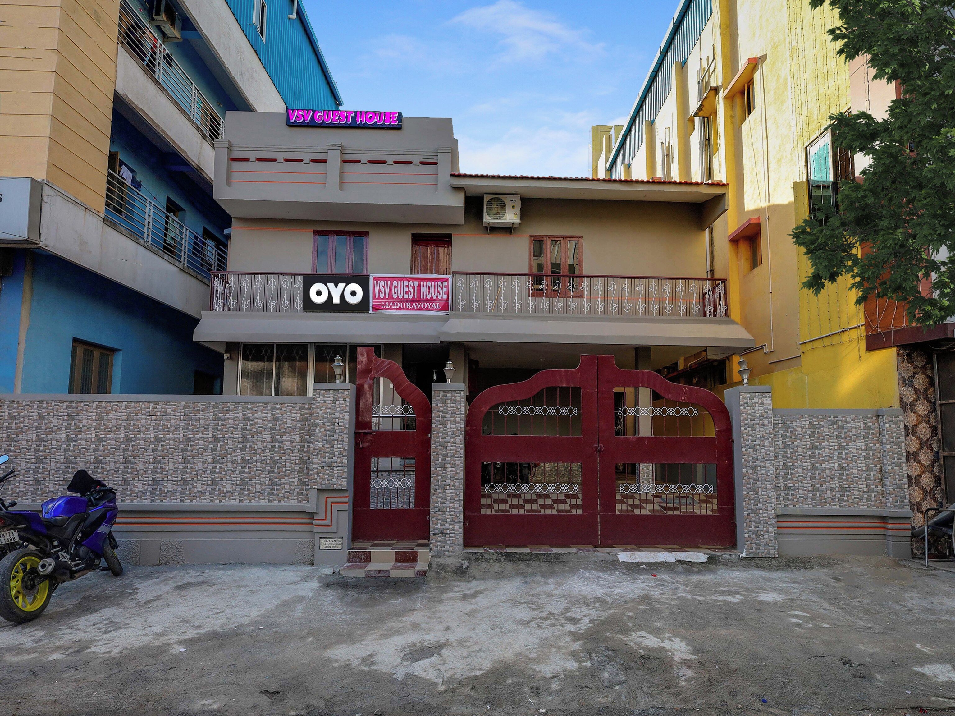 Un edificio de dos pisos con un letrero que dice 'VSV GUEST HOUSE' y 'OYO VSV GUEST HOUSE', indicando una casa de huéspedes.