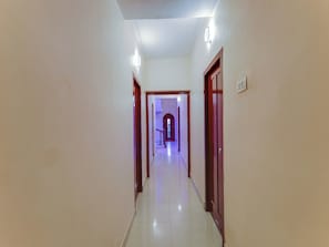 A corridor with doors on both sides, leading to a room with a window and a door at the end. - Hotel O Vsv Guest House Maduravoyal (Chennai)