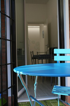 A blue folding table with a chair, a glass door, and a view into a room with a table and chairs. - New Listing (Roma)