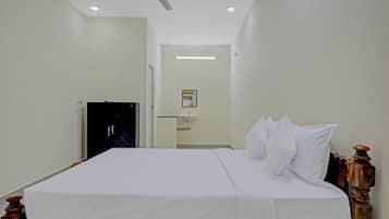 Une chambre avec un lit simple, un ventilateur de plafond, une porte et une petite table de chevet.