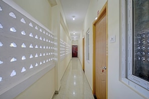 A hallway with a patterned wall, a wooden door, and a tiled floor.
