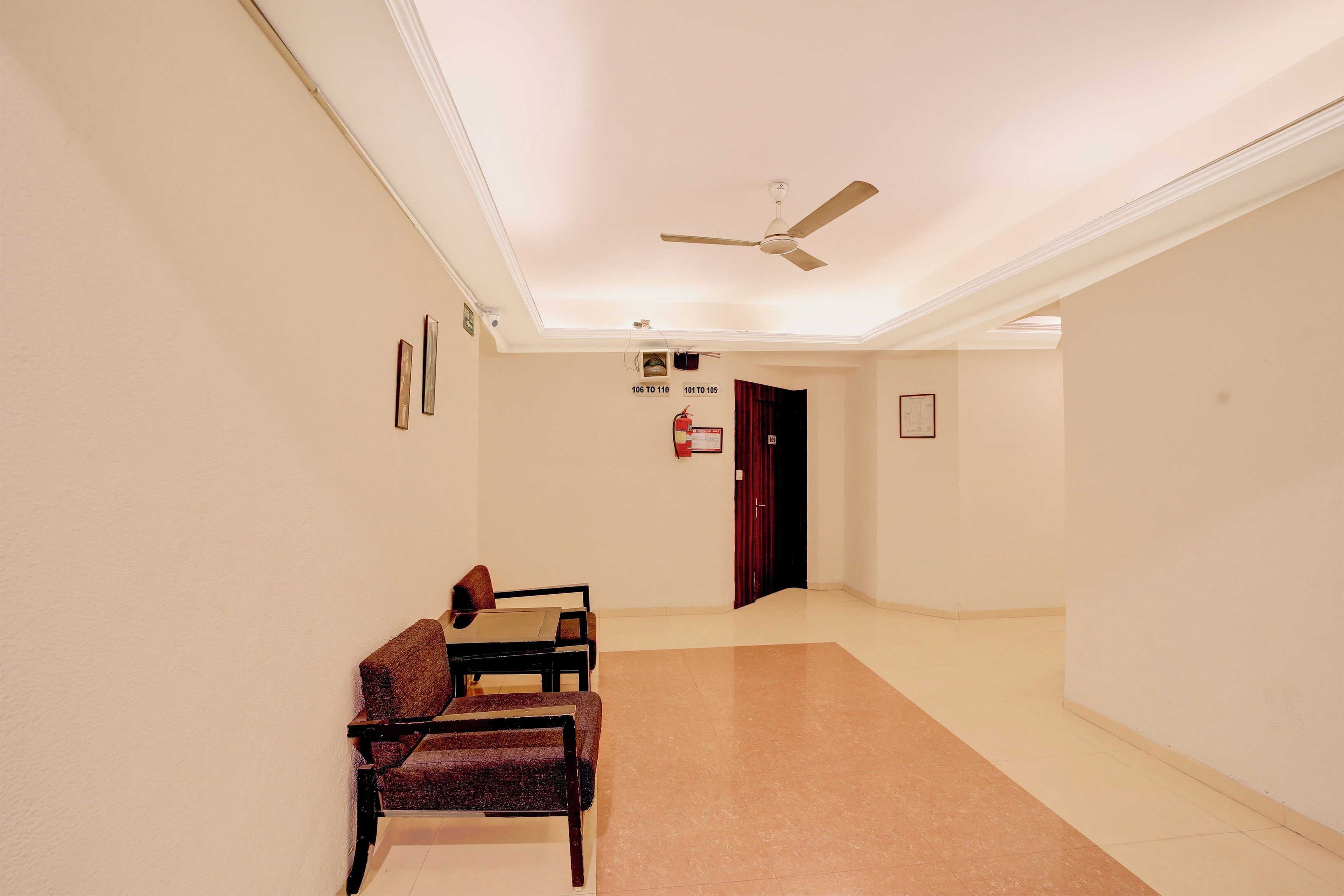 A hallway with a ceiling fan, a fire extinguisher, and a door marked with room numbers.