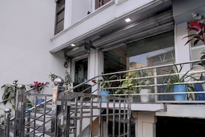 A building with a metal staircase leading to a door, surrounded by potted plants.