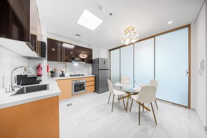 Une cuisine moderne dotée d’un îlot central, d’un coin repas avec une table en verre et d’un placard à portes coulissantes.