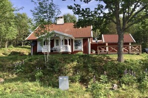 A house with a red roof, a porch, and a garden with purple flowers. - Holiday home in Gislaved with swimming pool (Gislaved)