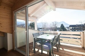 A balcony with a glass door, a table, and chairs. - Holiday apartment with 1 bedroom (Garmisch-Partenkirchen)
