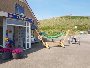 A building with a sign reading 'Vakantieburo' and a hammock set up outside. - Bungalow With 3 Bedrooms (Julianadorp)