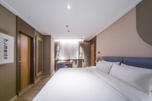 Una habitación de hotel con una cama grande, un escritorio con una silla y una ventana con cortinas.