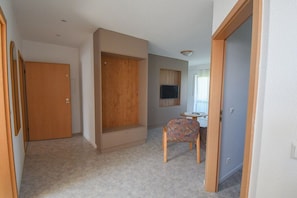 A room with a wooden wardrobe, a television mounted on the wall, and a patterned chair. - Holiday apartment with 2 bedrooms (Impflingen)