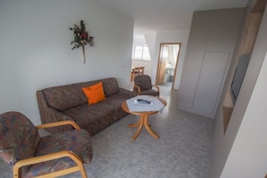 A living room with a sofa, two armchairs, a coffee table, and a TV. - Holiday apartment with 2 bedrooms (Impflingen)