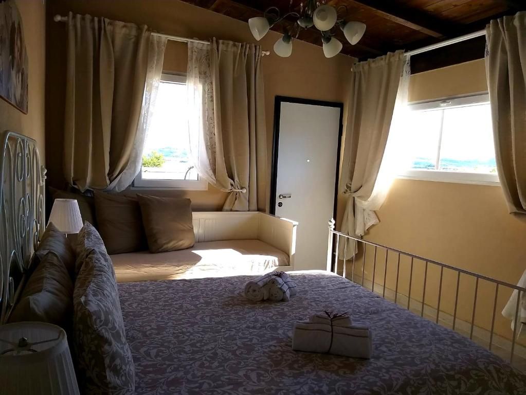 Un dormitorio con cama, mesita de noche, lámpara, ventana con cortinas y puerta.