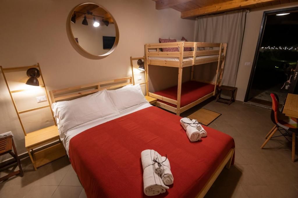 Ein Zimmer mit einem Etagenbett, einem Einzelbett, einem Schreibtisch und einem Stuhl.