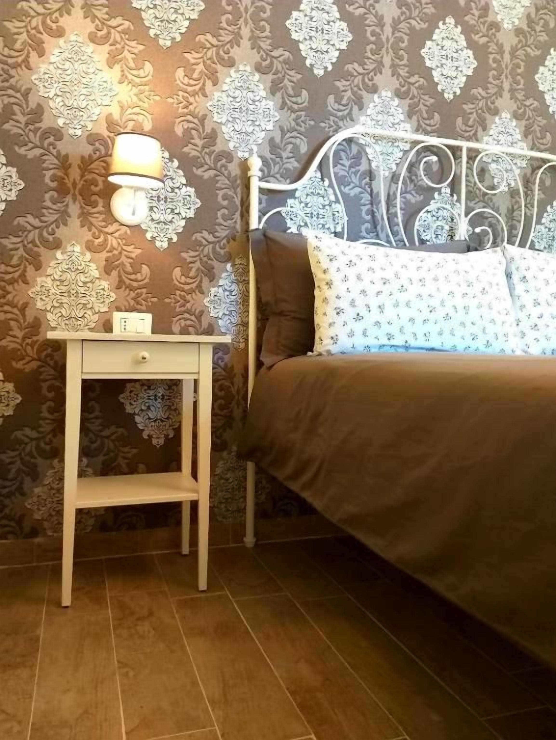 A bedroom with a bed, a nightstand, and a wall-mounted lamp.