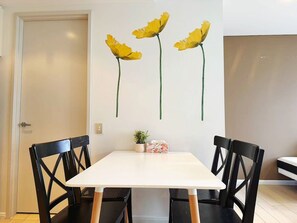 A dining area with a white table, black chairs, and a wall-mounted flower decoration. - Light Filled Zetland Retreat (Zetland)
