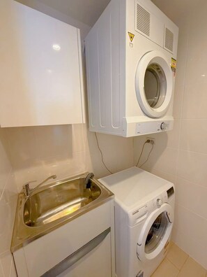 A compact laundry area with a built-in washing machine and a sink. - Light Filled Zetland Retreat (Zetland)