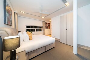 Un dormitorio moderno con una cama grande, un ventilador de techo y una mesita de noche con lámpara.