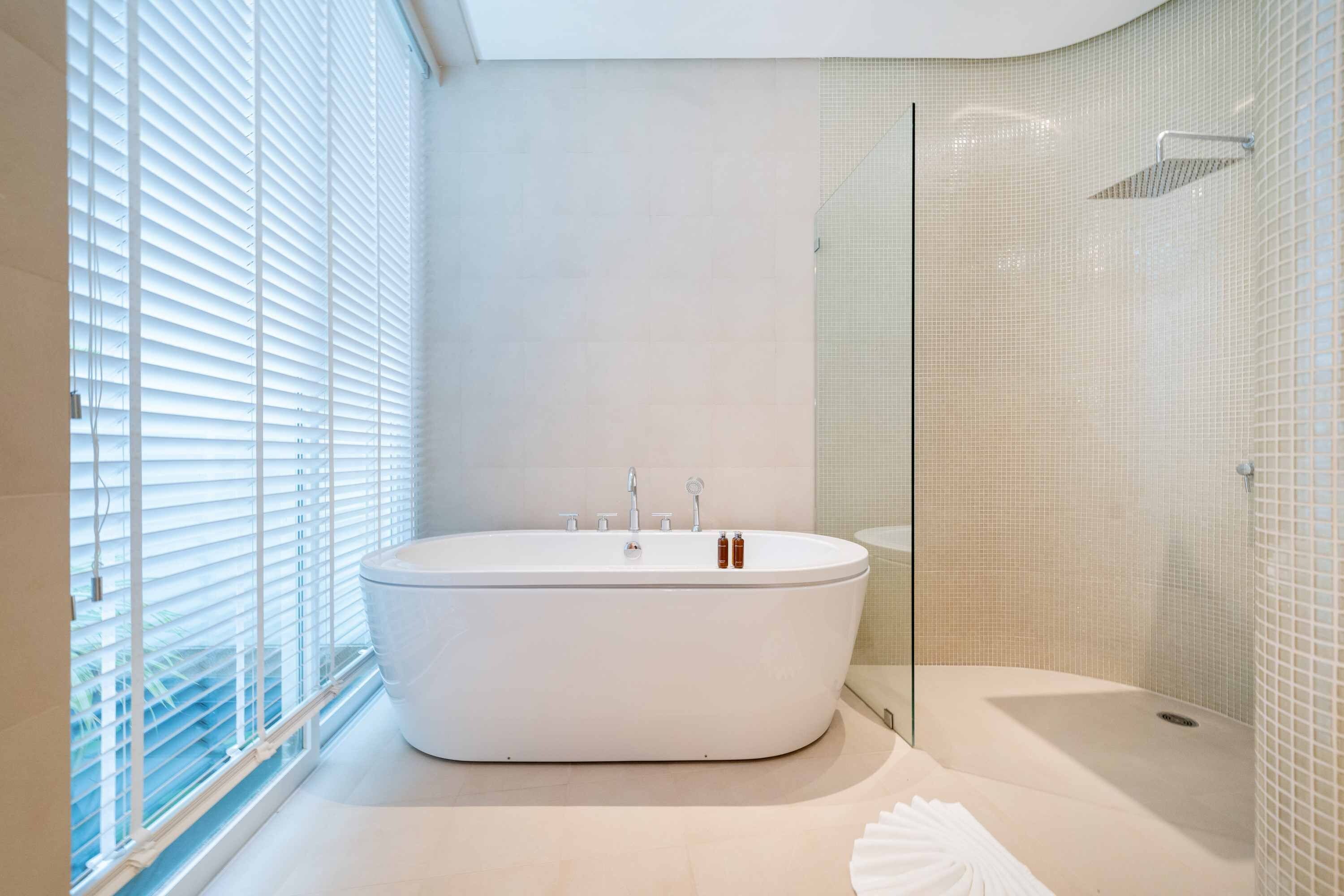 Ein modernes Badezimmer mit einer freistehenden Badewanne, einer Duschkabine aus Glas und einer Aussicht durch große Fenster.