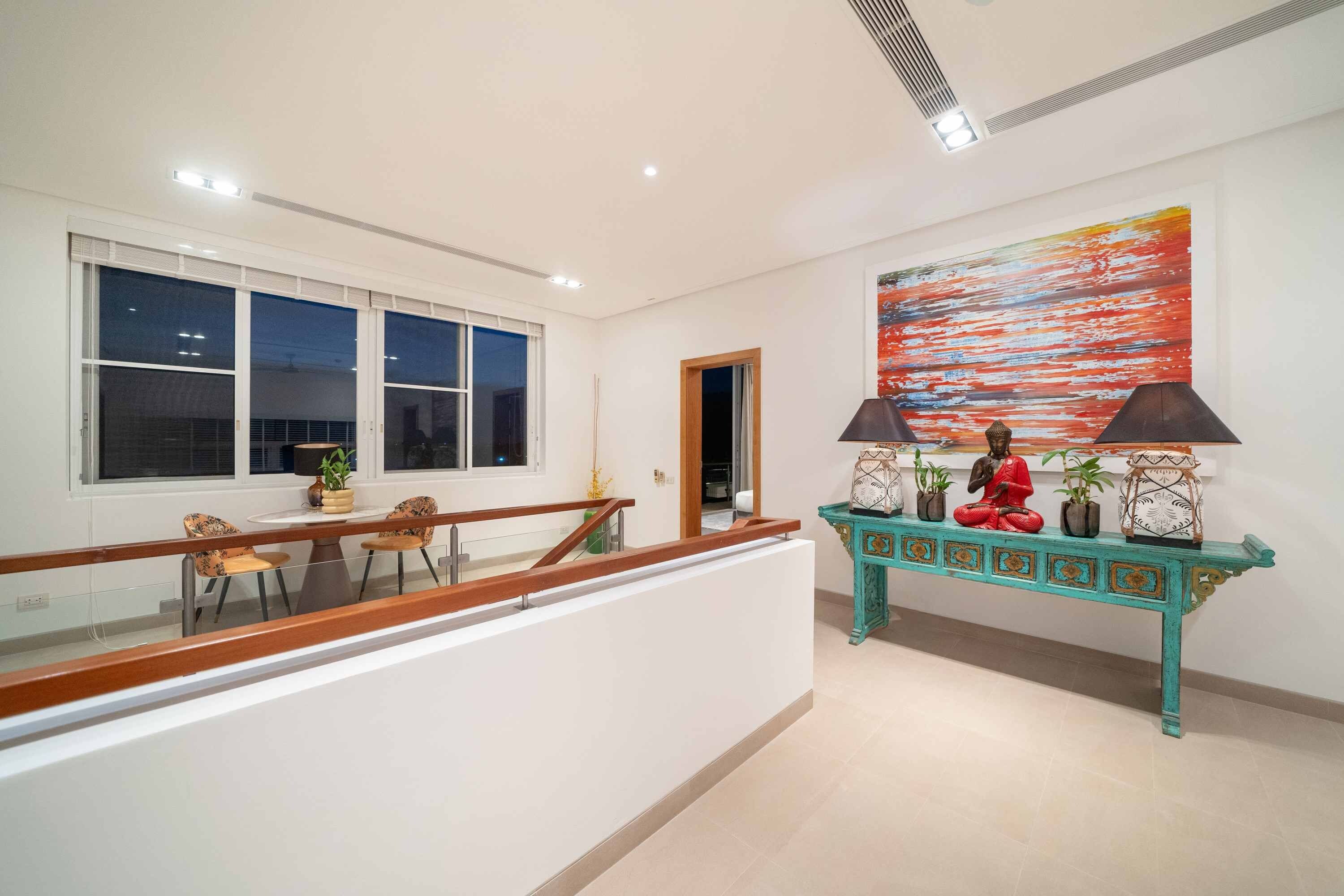 A modern interior with a dining area, a staircase, and a decorative console table with a Buddha statue.