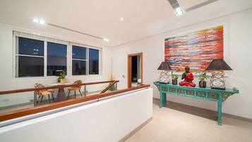 A modern interior with a dining area, a staircase, and a decorative console table with a Buddha statue.