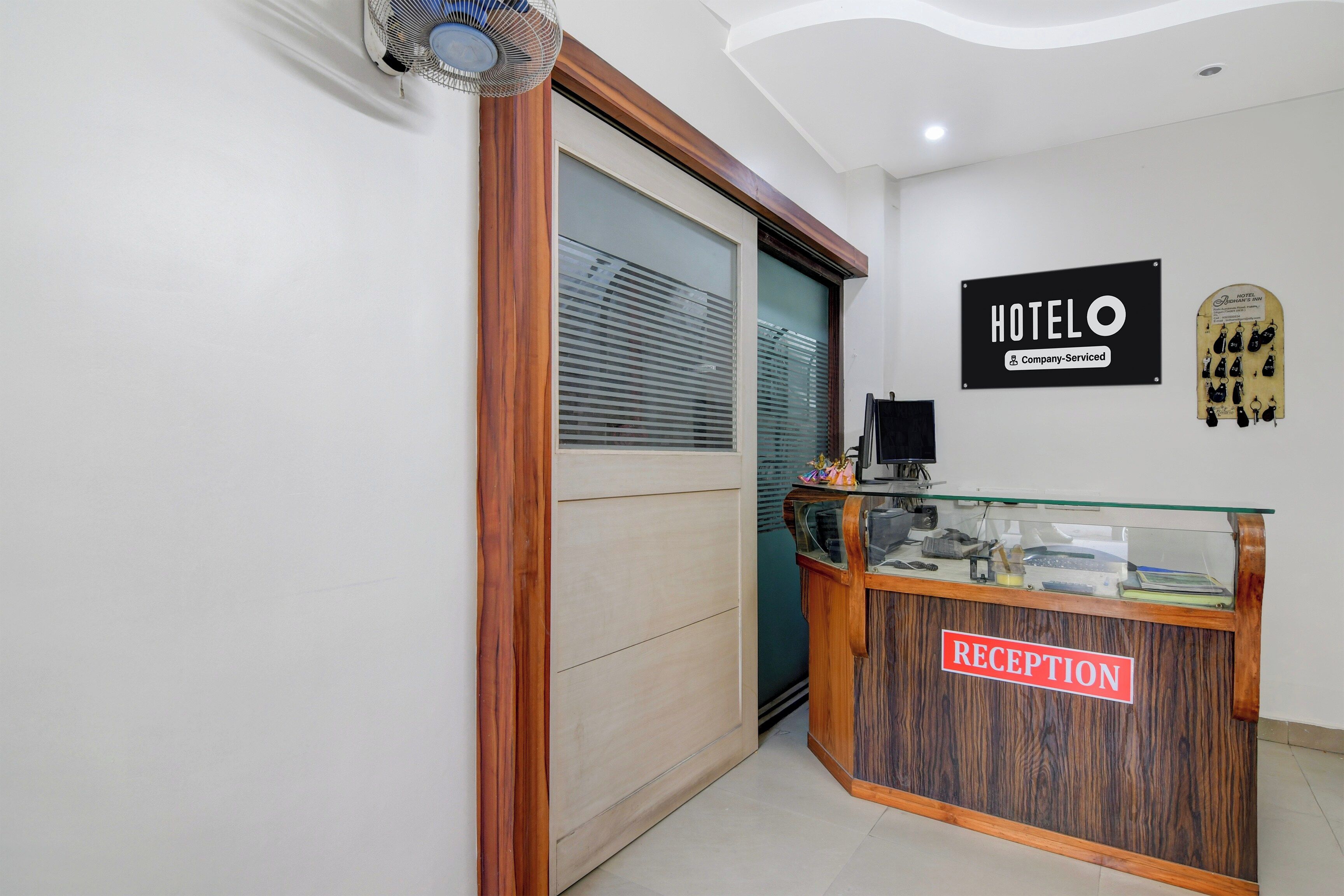 Una zona de recepción con un mostrador de madera, un letrero que indica que es un hotel y una exhibición de llaves.