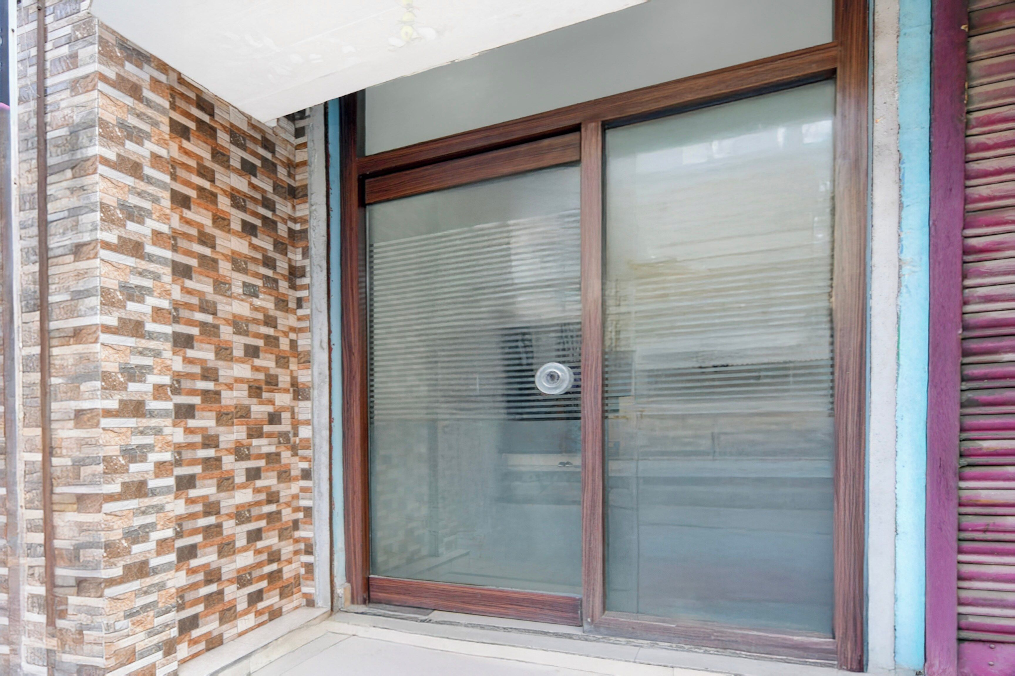 Entrada de un edificio con puerta de vidrio y pared de ladrillo con diseño.