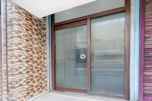 A building entrance with a glass door and a patterned brick wall. - Hotel O Kanchenjunga Stadium (Siliguri)