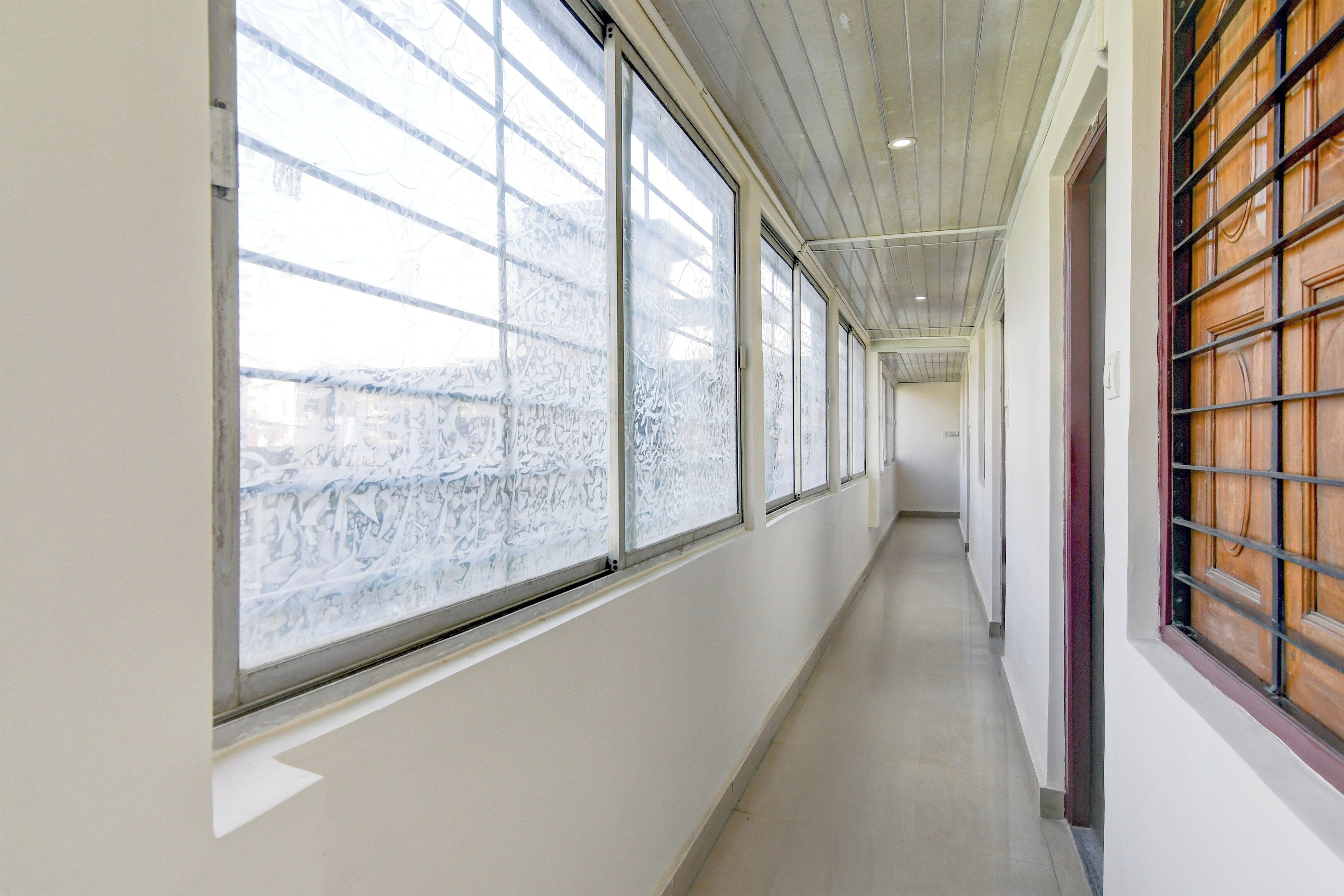A corridor with large windows on one side and a wooden door on the other.
