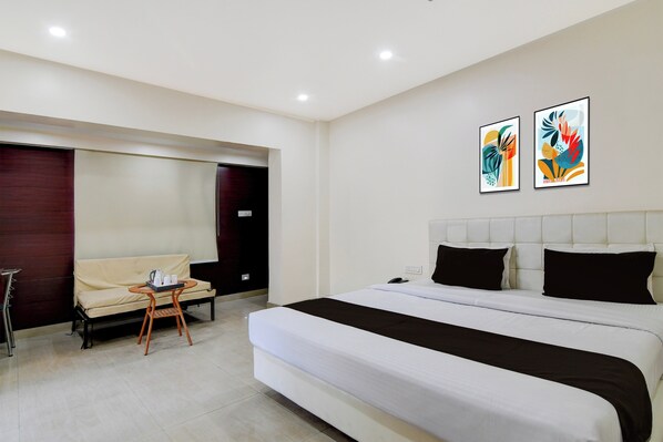 A hotel room with a bed, a sofa, a small table with a tray, and two wall-mounted artworks. - Hotel O Kanchenjunga Stadium (Siliguri)